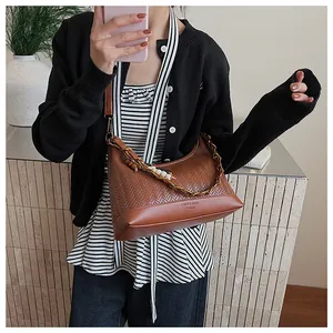 Détail du sac seau marron tressé avec chaîne dorée et perles porté à l'épaule