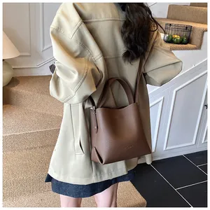 Brown litchi grain leather bucket bag styled with a khaki coat for a modern casual look