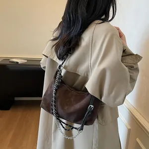 Sac dumpling marron foncé mat avec chaîne argentée et bandoulière réglable sur modèle
