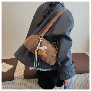 Brown leopard-embossed shoulder bag styled with a cute teddy bear charm on grey blazer
