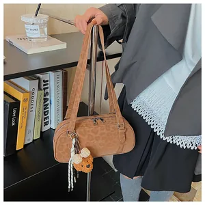 Detail of leopard print suede shoulder bag with plush bear charm in a lifestyle setting