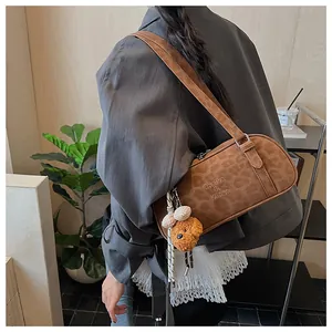 Detail view of leopard print shoulder bag with a cute brown plush bear charm and brand logo