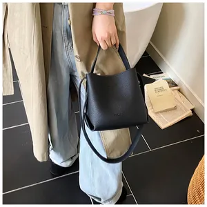 Litchi pattern leather bucket bag held by a model in a minimalist lifestyle indoor setting