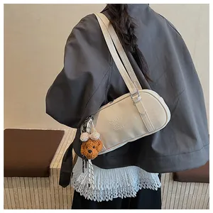 Detail of cream shoulder bag with plush dog charm and brand logo on textured leather