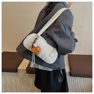 Close-up of cream leather shoulder bag with silk scarf and plush bear charm detail