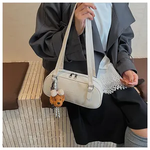 Detail of off-white bowling underarm bag with brand embossing and bear charm