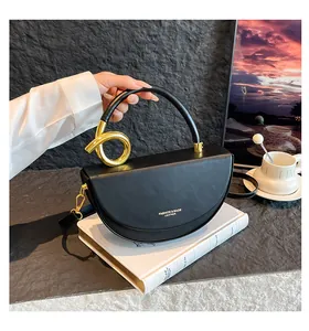 Détail du sac selle en cuir noir avec une poignée design unique en métal doré torsadé