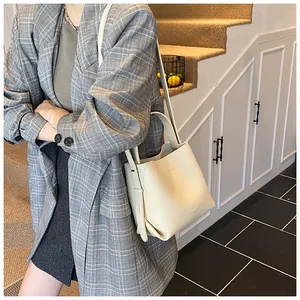 Detail of cream lychee texture leather bucket bag with top handle and slim strap