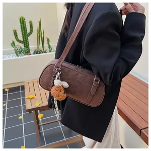 Detailed close-up of brown suede bowling bag with brand embossing and cute dog charm