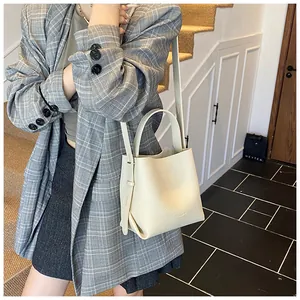 Close-up of a cream-colored lychee leather bucket bag with top handle and strap