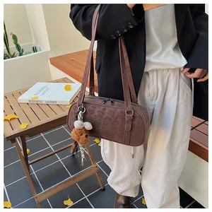 Brown bowling bag with leopard texture and bear charm worn by model in outdoor setting