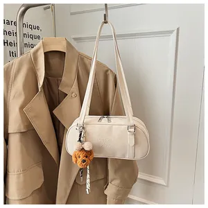 Detailed view of cream leather shoulder bag with brand logo and cute puppy pendant