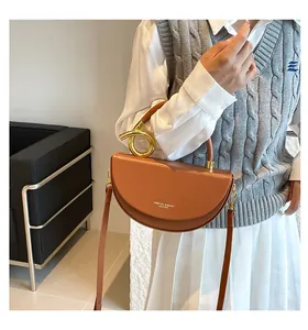 Sacoche marron en cuir avec poignée à nœud en métal doré porté par un mannequin