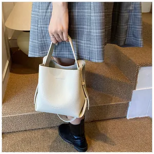 Detail of white lychee leather bucket bag showing refined texture and minimalist style