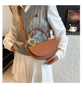 Sacoche selle en cuir marron portée avec détails en métal doré et bandoulière