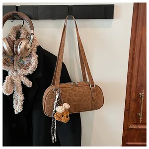 Detailed close-up of a brown leopard print bowling bag with a cute bear pendant charm