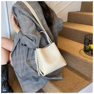 Close-up of cream lychee pattern bucket bag with tassel detail on grey plaid suit