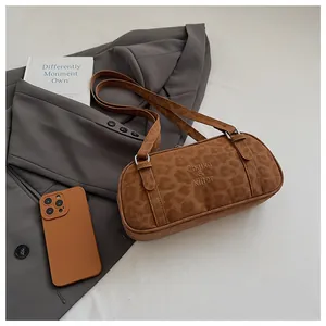 Detail of a brown leopard print shoulder bag with logo on a grey blazer background