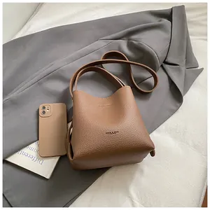 Close-up of brown lychee grain leather bucket bag with brand logo and accessories