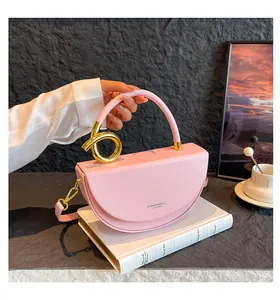 Detail of pink half-moon saddle bag with golden knot hardware and smooth leather finish