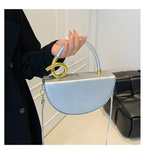 Silver saddle bag detail with curved metal handle and gold twist hardware accents