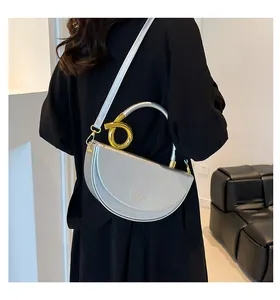 Polished silver crescent saddle bag with metallic gold knot handle worn over black coat