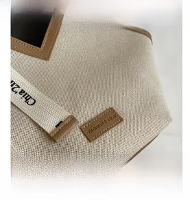 Détail du sac cabas en toile blanc cassé avec patch en cuir et bandoulière brodée