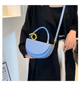 Détail du sac croissant bleu clair avec quincaillerie dorée torsadée et bandoulière