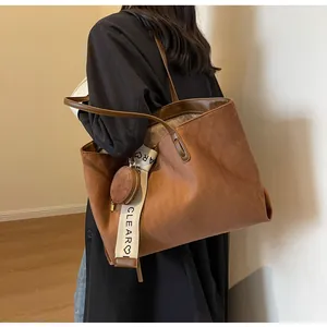 Macro detail of brown suede tote bag with diamond pattern and heart strap decoration