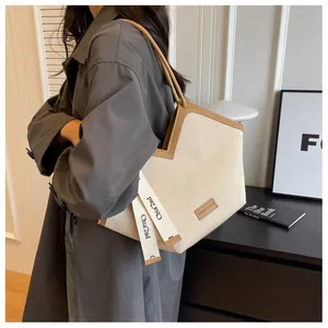 Détail du sac fourre-tout en toile beige avec bordure en cuir marron et bandoulière