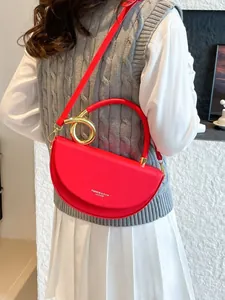 Red leather half-moon saddle bag with golden circular handle and shoulder strap