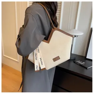 Détail du sac cabas en toile avec garniture en cuir marron et sangle décorative