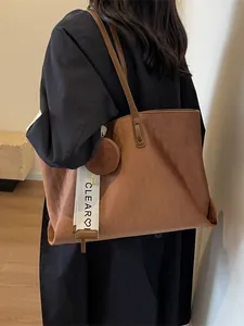 Brown faux suede tote bag with diamond pattern and small pouch worn by a model