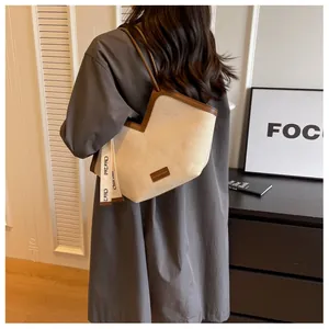 Sac fourre-tout en toile beige avec bordure en cuir marron porté pour un style quotidien