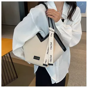 Détail du sac fourre-tout en toile crème avec bordure en cuir noir et design en V chic