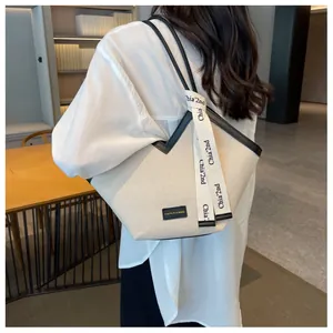 Détail d'un sac cabas en toile avec bordure en cuir noir et ruban décoratif lettré