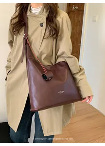 Deep brown leather tote bag with long straps worn on a beige trench coat