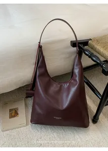 Detail of burgundy leather hobo bag featuring logo text and minimalist retro silhouette
