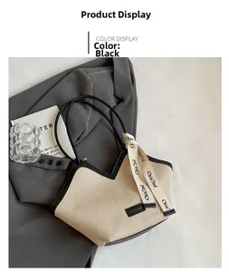 Détail d'un grand sac cabas en toile avec garniture en cuir noir sur fond de costume gris