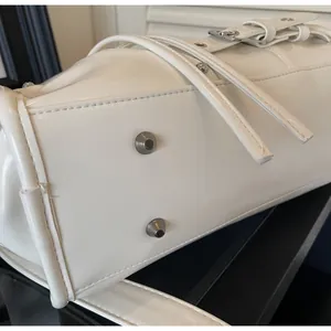 Detailed close-up of white PU leather bag bottom with silver metal protective studs
