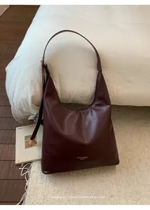 Detail view of burgundy leather hobo bag with minimalist logo and wide shoulder strap
