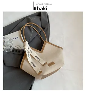 Détail du cabas en toile kaki avec bordure en cuir marron et lanières en ruban chic