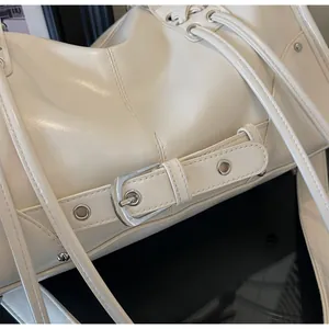 Detailed macro view of cream white glossy leather tote bag with silver buckle and eyelets