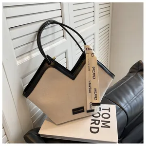 Détail du sac cabas en toile en V avec garniture en cuir noir et ruban logo élégant