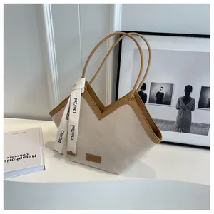 Détail du sac cabas en toile beige avec bordure en cuir marun et ruban décoratif