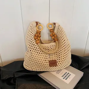 Hollow crochet beach tote bag with beaded handles on black leather texture