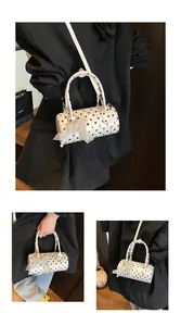 Detalle de bolso cilíndrico blanco de lunares con lazo de encaje y adornos de perlas