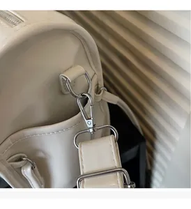 Detail of silver metallic hardware and wide strap on cream white faux leather shoulder bag