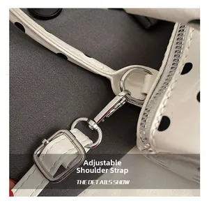 Detalle de correa ajustable con hebilla plateada en bolso blanco de lunares negros