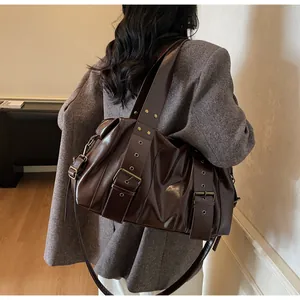 Dettaglio della borsa tote in pelle lucida marrone scuro con tracolla larga e fibbia